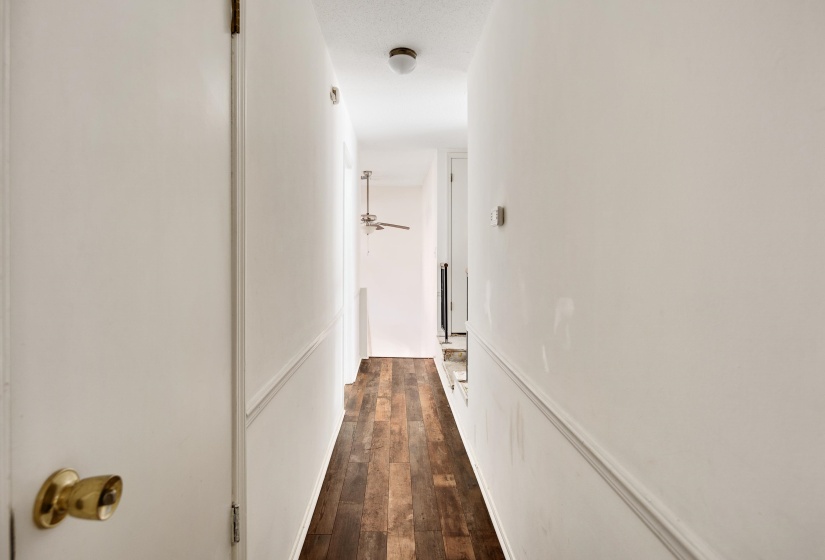 Hallway with dark wood-type flooring and a decorative wall