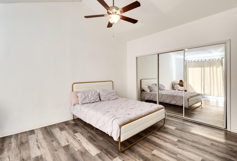 Bedroom with vaulted ceiling, wood finished floors, a closet, and a ceiling fan