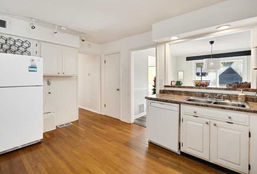 Kitchen featuring white cabinets, white appliances, light wood-type flooring, and dark countertops