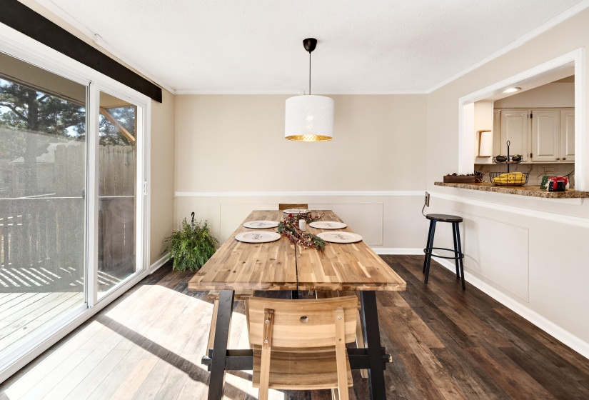 Dining area with dark wood-style flooring, wainscoting, and crown molding