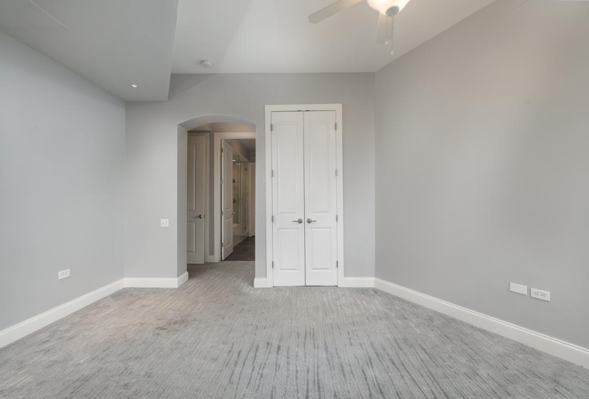 Unfurnished bedroom featuring arched walkways, carpet, a closet, and a ceiling fan