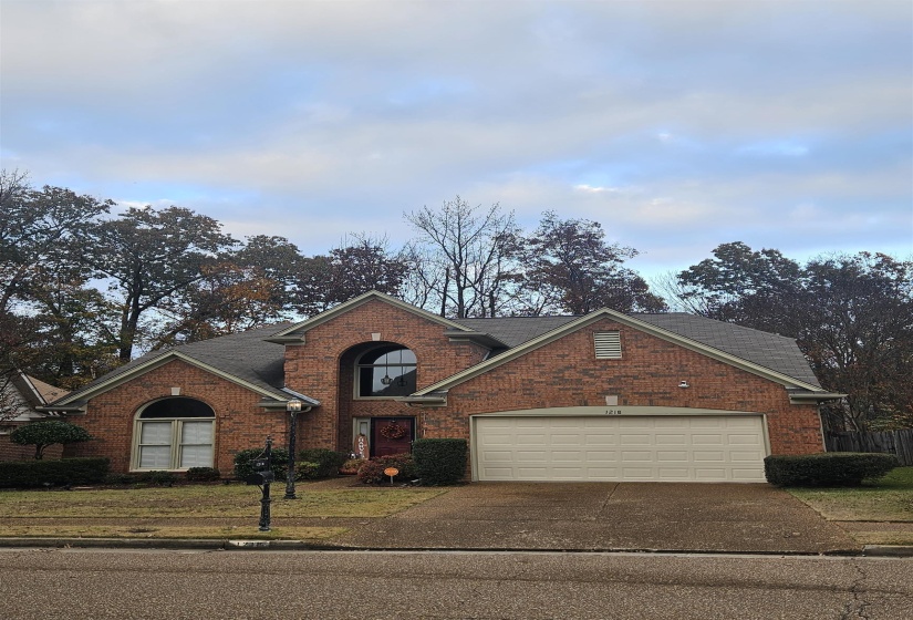 View of front facade featuring driveway, brick siding, and an attached garage