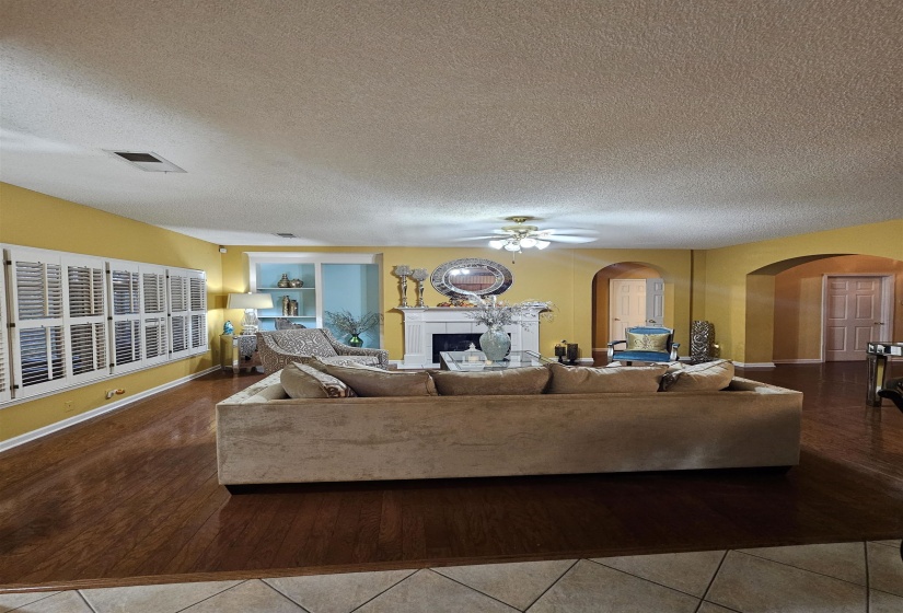Living area with hardwood / wood-style floors, a fireplace, arched walkways, a textured ceiling, and a ceiling fan
