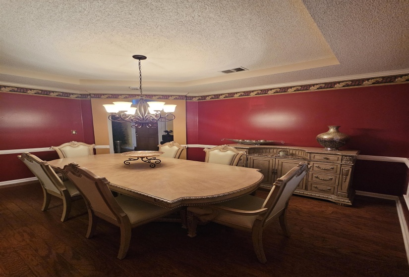 Dining room featuring a chandelier, a textured ceiling, dark wood-type flooring, and a raised ceiling