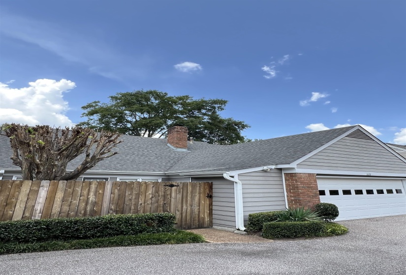 View of front of house featuring a shingled roof, a chimney, a garage, brick siding, and driveway