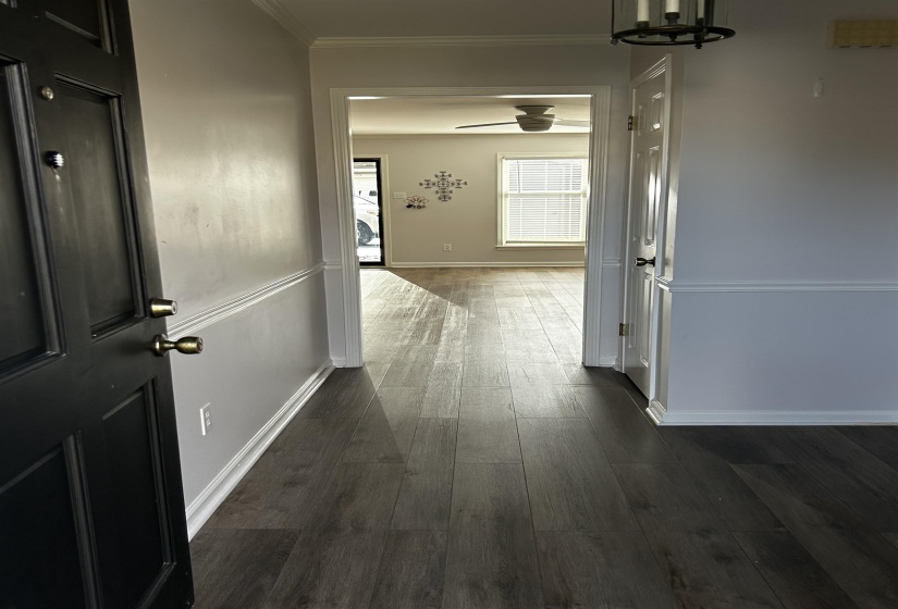 Hallway with dark wood-type flooring, crown molding, and a chandelier
