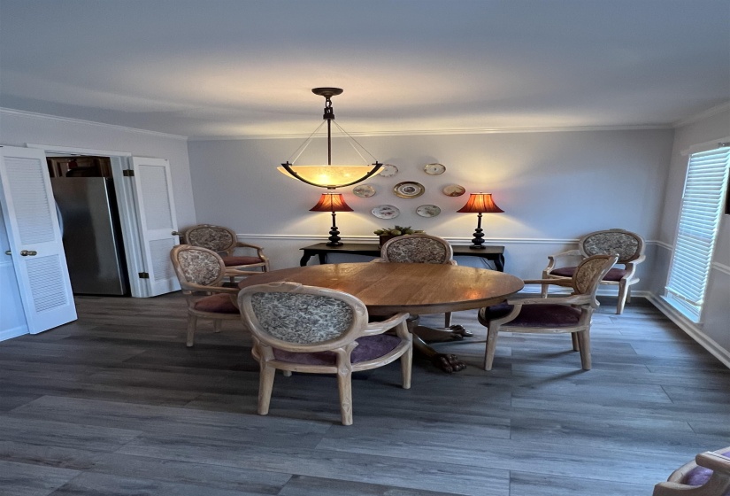 Dining space with crown molding and dark wood-style floors