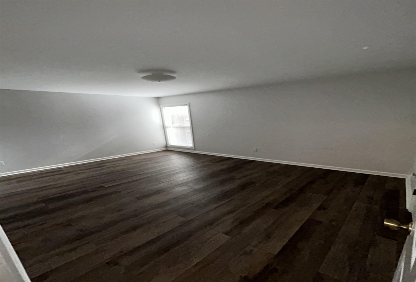 Spare room with dark wood-style flooring and baseboards