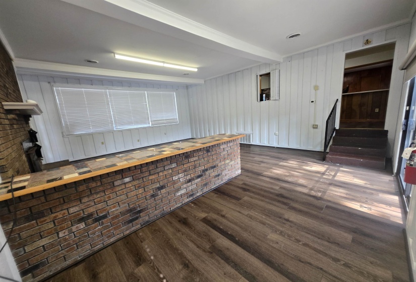 Bar with dark wood-type flooring, wooden walls, and stairs