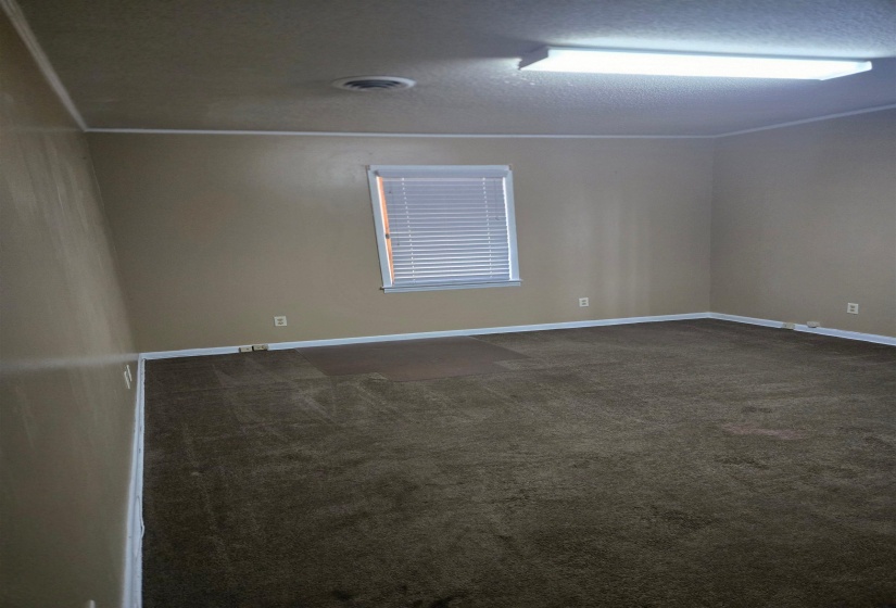 Empty room featuring dark colored carpet and a textured ceiling
