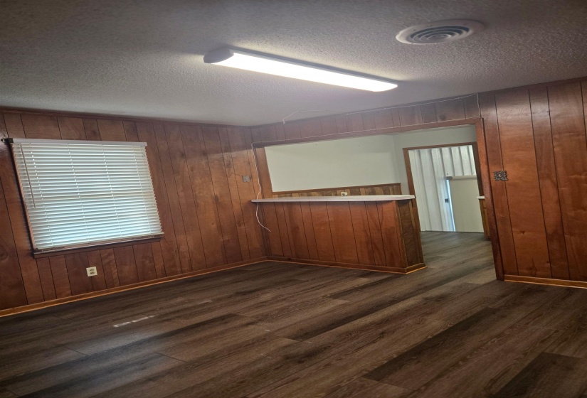 Unfurnished room featuring wooden walls, dark wood-type flooring, and a textured ceiling