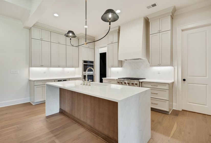 Kitchen featuring a sink, appliances with stainless steel finishes, light countertops, backsplash, and light wood-type flooring