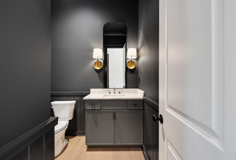Bathroom featuring a wainscoted wall, toilet, vanity, and wood finished floors