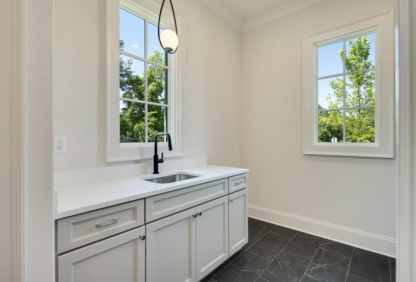 Bar featuring a sink, baseboards, dark marble finish flooring, and hanging light fixtures