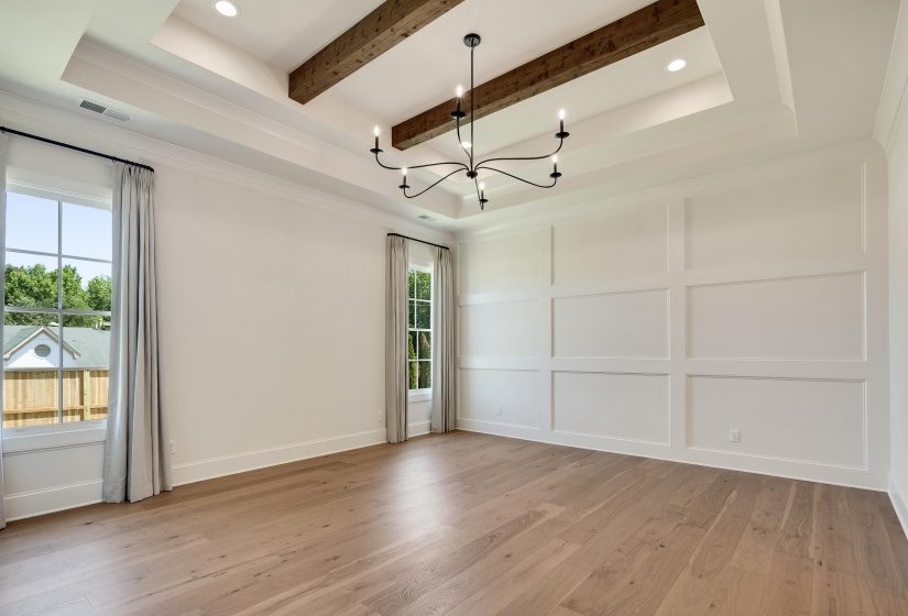 Unfurnished room featuring a chandelier, light wood-style flooring, beam ceiling, a decorative wall, and baseboards