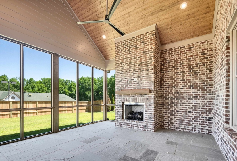 Unfurnished sunroom featuring an outdoor brick fireplace, ceiling fan, and vaulted ceiling