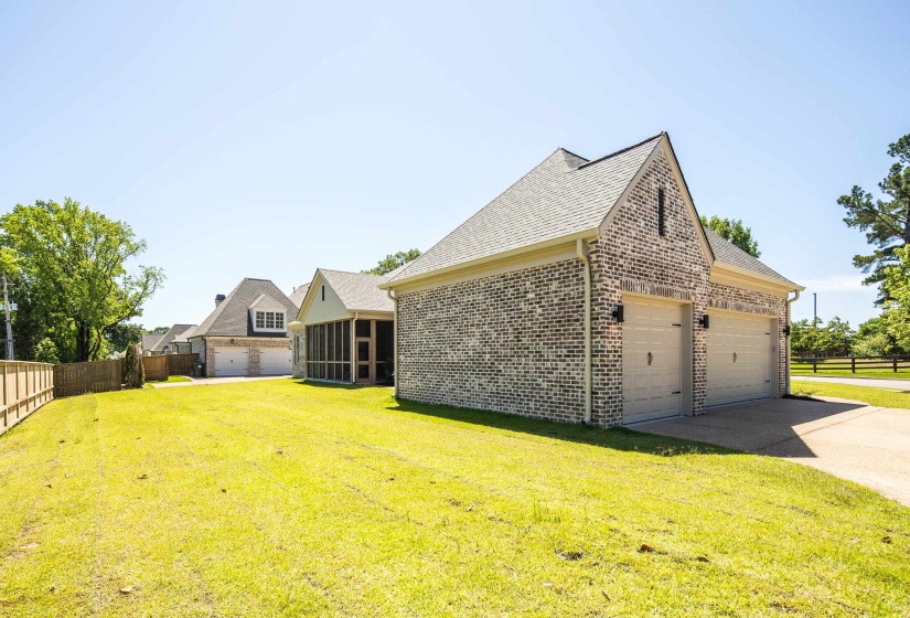 View of side of property featuring a sunroom, brick siding, roof with shingles, driveway, and a garage