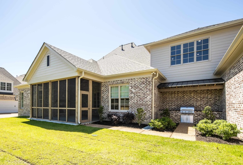Back of house with brick siding, a sunroom, a yard, and a standing seam roof