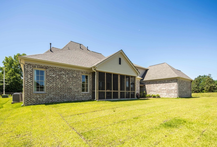 Back of property featuring brick siding, a yard, a sunroom, a shingled roof, and central AC