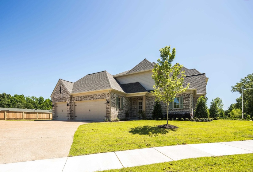 View of front of house with an attached garage, brick siding, driveway, and roof with shingles