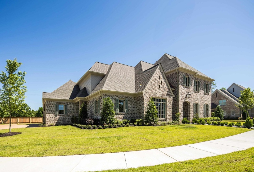 French country style house with brick siding and a shingled roof
