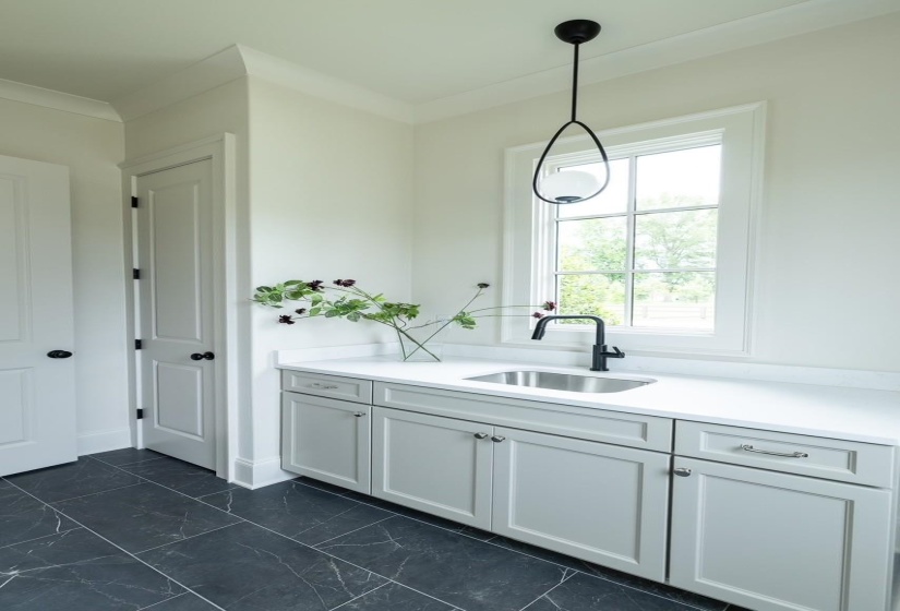 Kitchen with light countertops, pendant lighting, dark marble finish flooring, and ornamental molding
