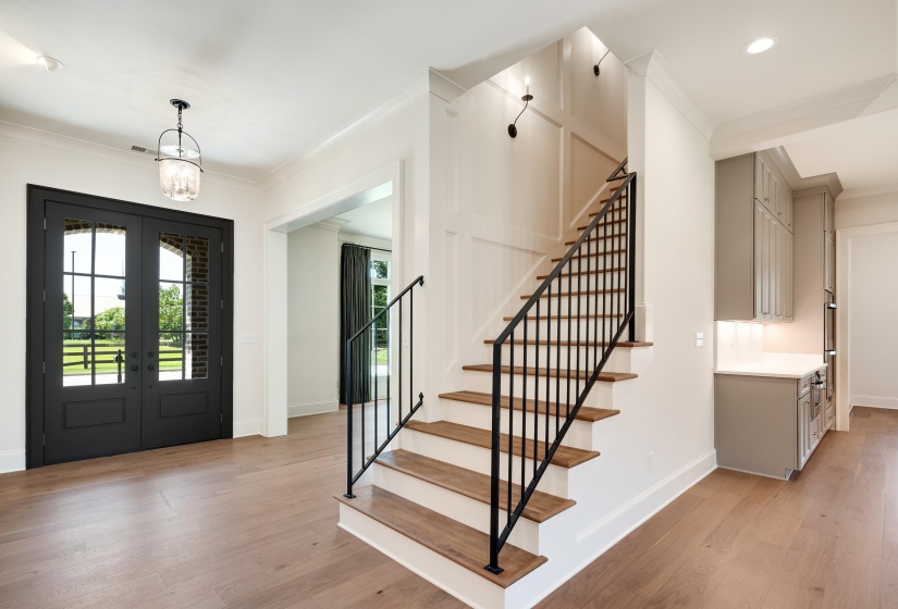 Foyer with french doors, ornamental molding, light wood-type flooring, stairs, and baseboards