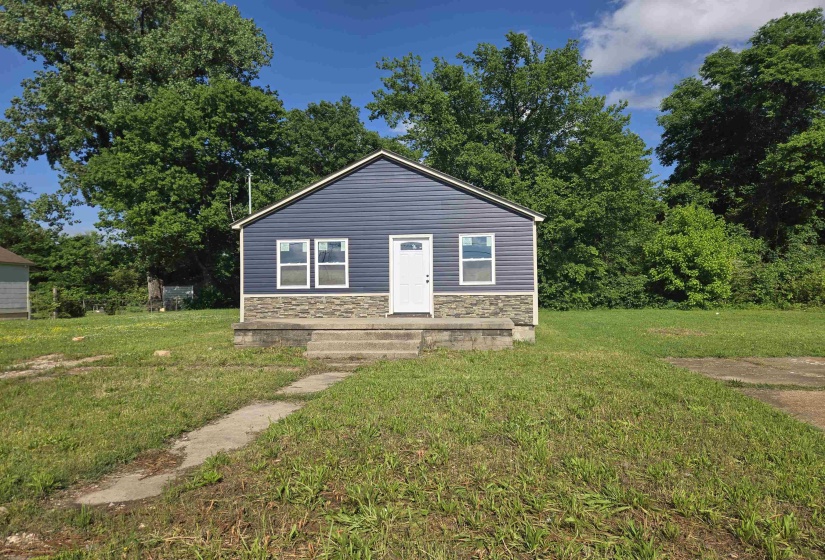 Bungalow with stone siding and a front yard