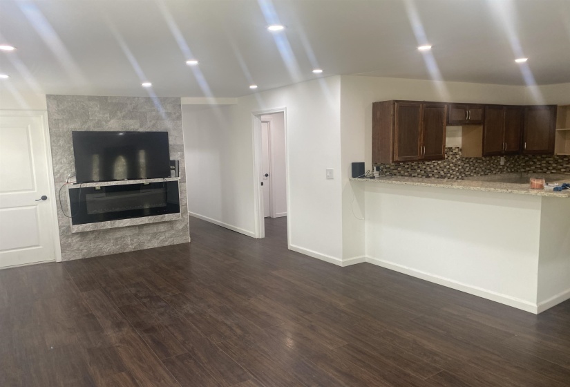 Unfurnished living room featuring a glass covered fireplace, baseboards, recessed lighting, and dark wood-type flooring