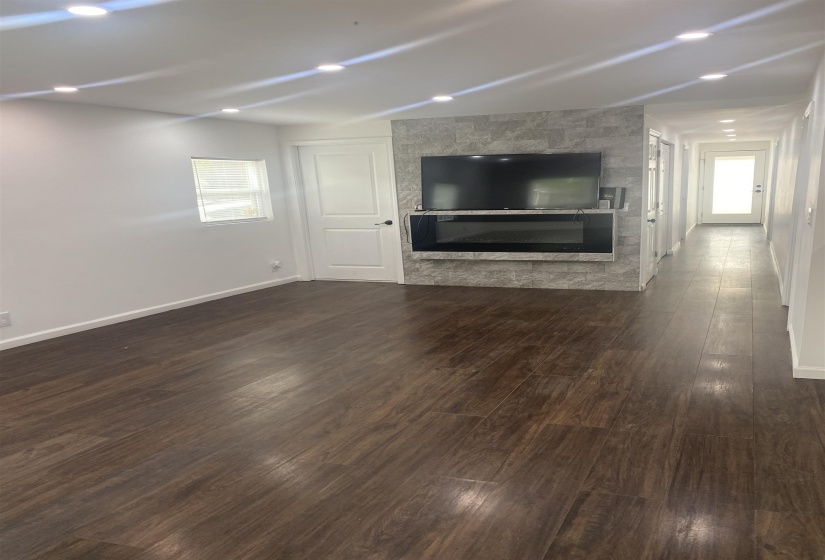 living room featuring a glass covered fireplace, baseboards, and dark wood-style floors