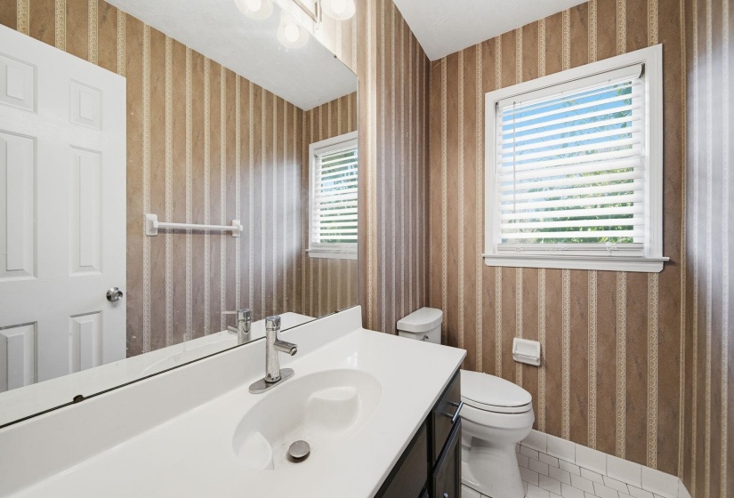 Half bath featuring wallpapered walls, vanity, and tile patterned flooring
