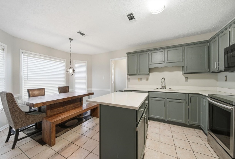 Kitchen with electric stove, a center island, pendant lighting, light tile patterned floors, and a textured ceiling