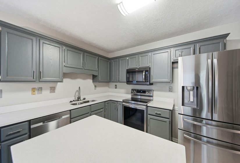 Kitchen with stainless steel appliances, gray cabinets, and a textured ceiling