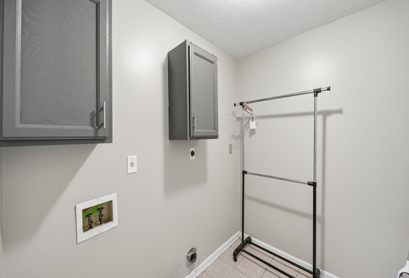 Washroom featuring cabinet space, light tile patterned floors, electric dryer hookup, washer hookup, and a textured ceiling