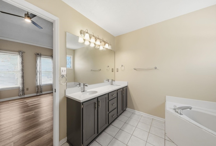 Full bathroom featuring double vanity, a bath, and a ceiling fan
