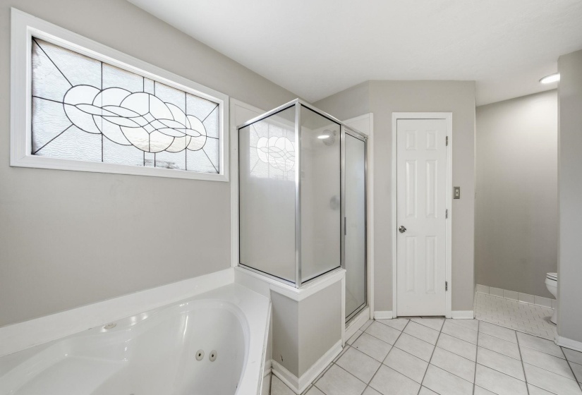 Full bathroom featuring a jetted tub, a shower stall, and light tile patterned floors