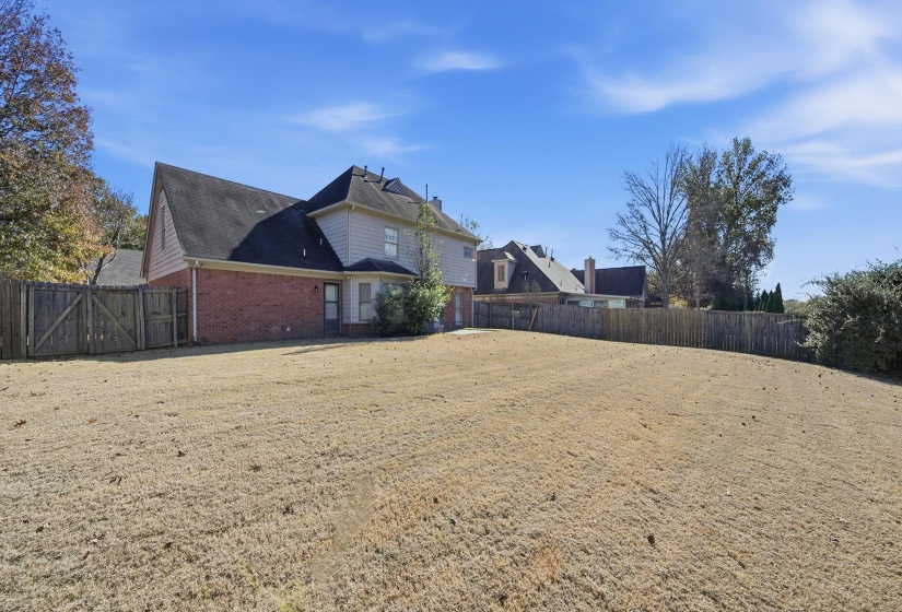 View of side of home featuring brick siding and a gate