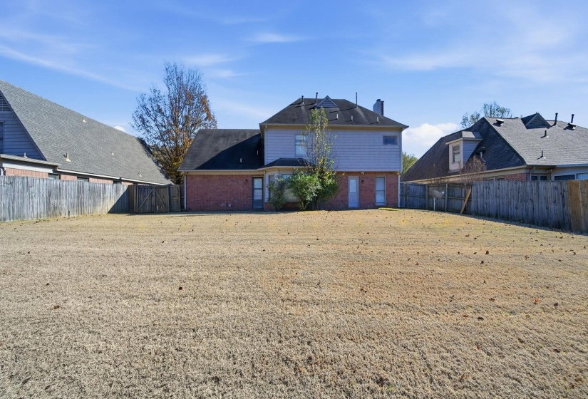 Back of house featuring brick siding and a fenced backyard