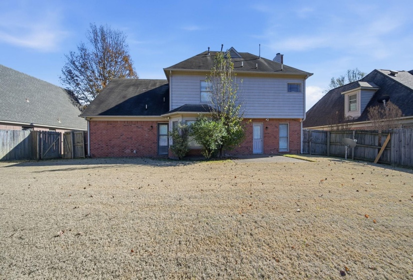 Rear view of house with a fenced backyard and brick siding