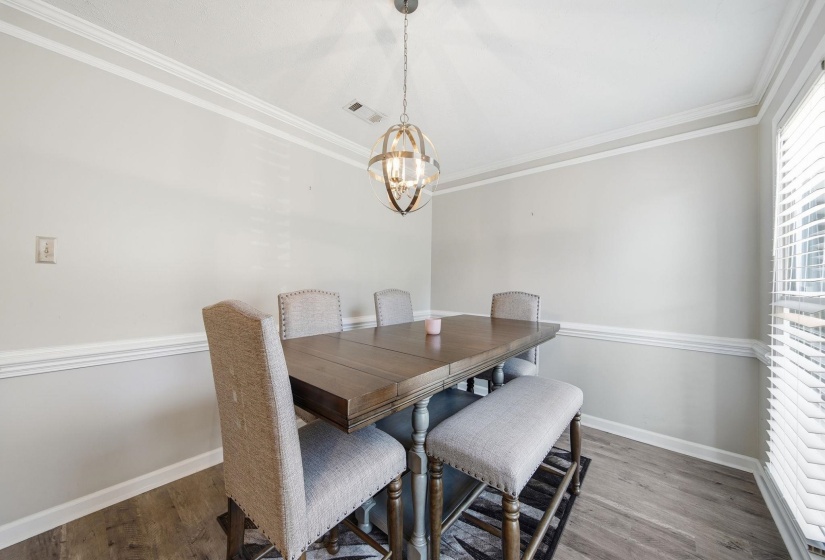 Dining area featuring light wood-type flooring, ornamental molding, and a chandelier