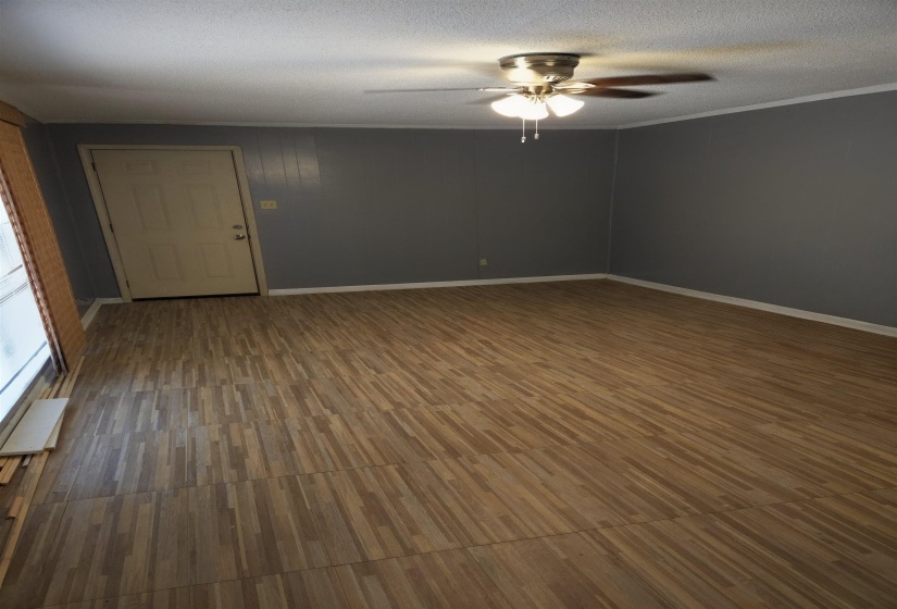 Empty room with ceiling fan, dark wood-style flooring, and a textured ceiling