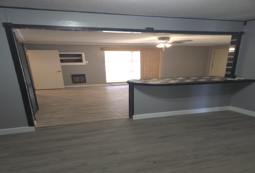 Kitchen with a ceiling fan, a fireplace, a textured ceiling, dark wood-style flooring, and heating unit