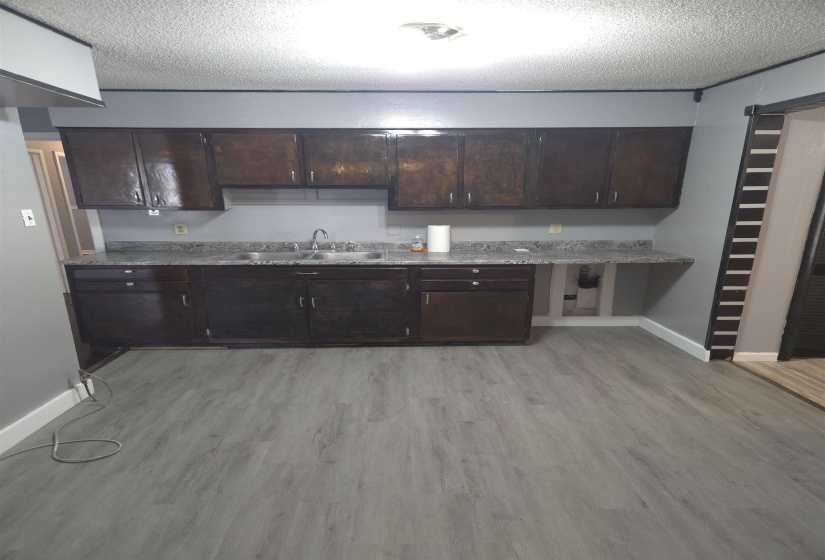 Kitchen with dark wood finish cabinets, a textured ceiling, and light wood finished floors