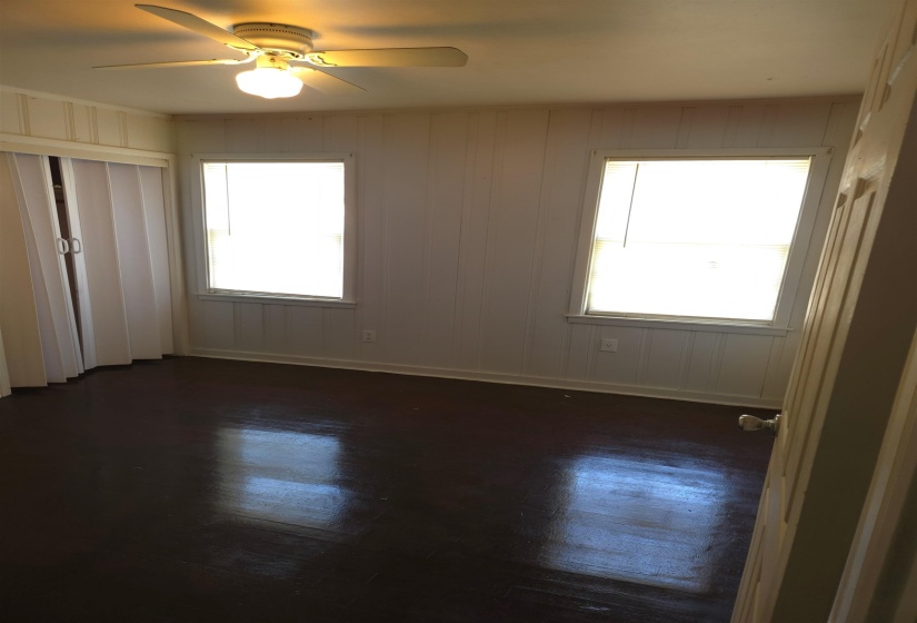 Unfurnished bedroom with dark wood-style flooring, a ceiling fan, and multiple windows
