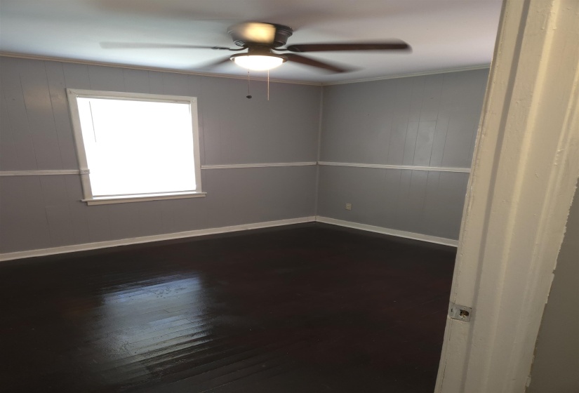 Spare room featuring dark wood-style flooring, ceiling fan, and wood walls