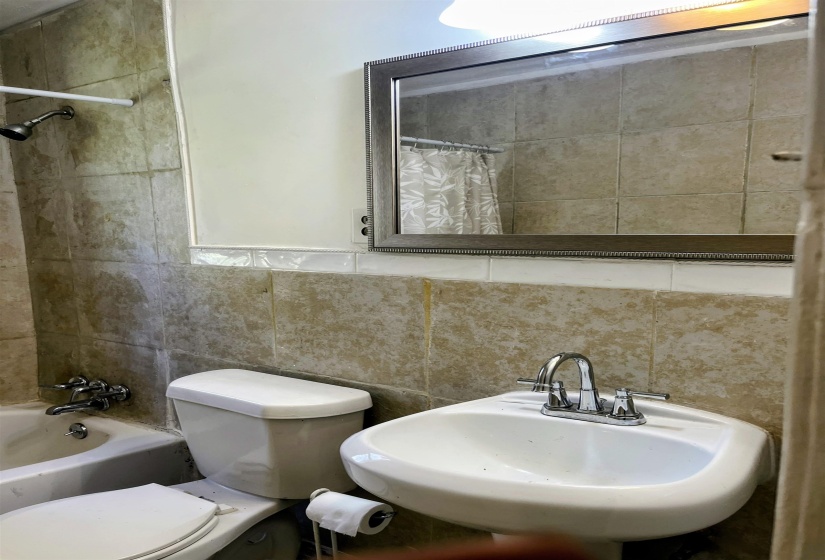 Full bathroom featuring shower / bath combo with shower curtain and tile walls
