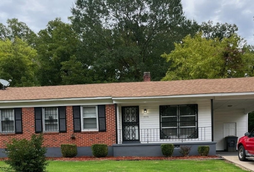 Ranch-style house with a porch, a carport, a chimney, and brick siding