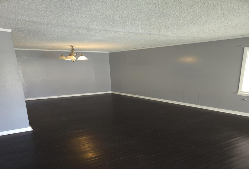 Spare room with ornamental molding, dark wood-type flooring, a textured ceiling, and a chandelier