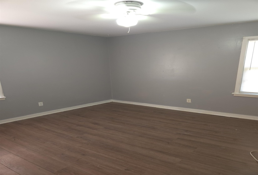Spare room featuring dark wood-type flooring and baseboards