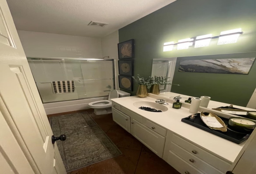 Bathroom featuring vanity, enclosed tub / shower combo, and dark tile patterned floors